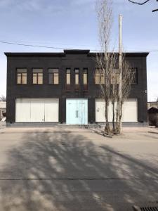 a black building with two garage doors and a tree at Gyumri Moderna in Gyumri