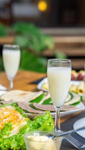 a table with plates of food and glasses of milk at Vilona Nature Villa in Dambulla