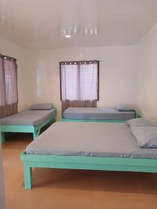 a room with three beds in a room at Pamilacan Vacay in Baclayon