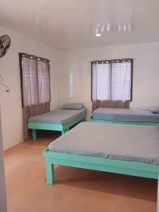 a room with two beds and two windows at Pamilacan Vacay in Baclayon