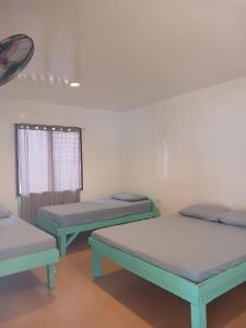 three beds in a room with a window at Pamilacan Vacay in Baclayon +6 photos