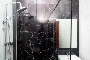 a bathroom with a shower with a black marble wall at Urbanview Grand Lotus Hotel by RedDoorz in Purwokerto +118 photos