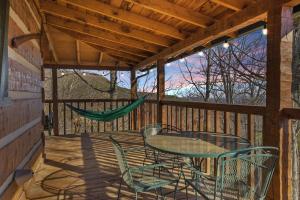 a porch with a hammock and a table and chairs at Somewhere In Time cabin in Sevierville