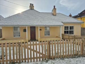 a yellow house with a wooden fence at Crossing Cottage, Aldeburgh in Aldeburgh