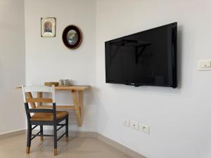 a tv on a wall with a chair and a table at Le cocon éclatant in Sfax