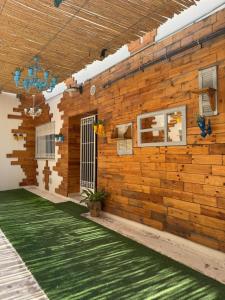 a room with a wooden wall and a green carpet at Le cocon éclatant in Sfax