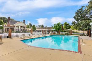 a swimming pool with chairs and a house at Rodeway Inn Williamsburg Historic Area in Williamsburg