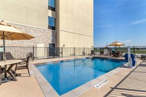 a swimming pool with tables and umbrellas on a building at Comfort Suites San Antonio Ft Sam Houston-SAMMC Area in San Antonio