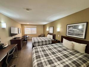 a hotel room with two beds and a desk at Rodeway Inn & Suites in Kamloops