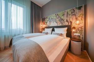 a bedroom with a large bed with a large painting on the wall at Vienna House Easy by Wyndham Augsburg in Augsburg