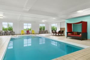 ein großer Pool in einem Zimmer mit Stühlen und Tischen in der Unterkunft Days Inn by Wyndham Oromocto Conference Centre in Oromocto