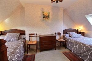 a bedroom with two beds and a dresser and two chairs at Le paradis in Plouguenast