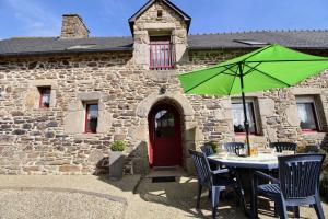 a table with a green umbrella in front of a building at Le paradis in Plouguenast
