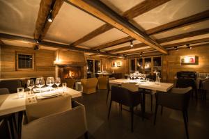 um restaurante com mesas e cadeiras brancas e uma lareira em Les Mazots de la Source & Spa em Vercorin