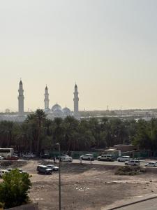 a parking lot with cars and mosques in the background at قمرة قباء Quba moon4 in Medina