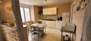 a kitchen with a table and a white refrigerator at Le logis in Plouguenast +20 photos