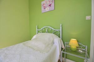 a green bedroom with a bed and a lamp at Le logis in Plouguenast