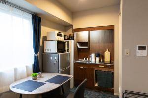 a small kitchen with a table and a refrigerator at Tanuki Inn Korien Kyoto Osaka in Neyagawa