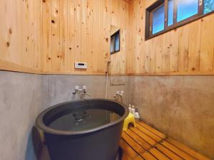 a bathroom with a tub in a wooden wall at shoya yamaguchi in Koibuchi