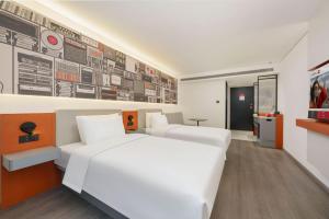 a bedroom with two beds and a wall with posters at Ibis Dalian Development Zone Wanda Plaza in Jinzhou
