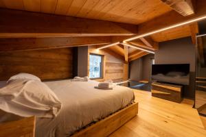a bedroom with a large bed and a flat screen tv at Le Suites de San Campel RTA in Ponte di Legno