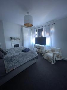 a bedroom with a bed and a desk with a television at Artsy Minimalist Suite in Southend-on-Sea