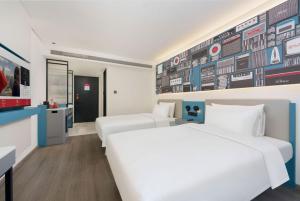 two beds in a room with a wall with hockey signs at Ibis Dalian Development Zone Wanda Plaza in Jinzhou