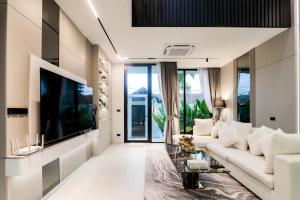 a living room with a white couch and a flat screen tv at Indiluxe pool villa in Pattaya South