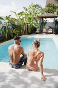 a man and a woman sitting next to a swimming pool at Emerald Villas by Paje Emerald Escapes Ltd in Paje +149 photos