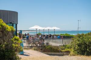 a group of people sitting at a beach bar with umbrellas at Blue Horizons at Ocean Grove in Ocean Grove