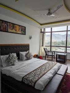 a bedroom with a large bed with a large window at Hotel The White Castle Kargil in Kargil +18 photos