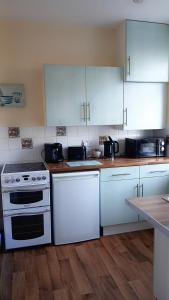 a kitchen with white appliances and wooden floors at Ashton Holiday Flats Seaviews in Bridlington