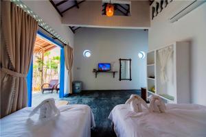 a bedroom with two beds and a tv in it at Cashew Tree Bungalow in Hoi An