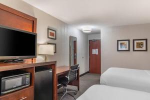 a hotel room with a bed and a desk with a television at Comfort Inn University in Amherst