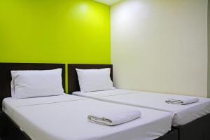 two beds in a room with a green wall at Rana Hotel in Sampong