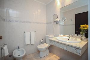a white bathroom with a sink and a toilet at Aparthotel Barracuda in Ponta Delgada