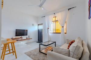 a living room with a couch and a tv at Wendy's Da-Azizi Homes Diani in Diani Beach