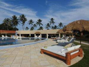 a resort with a swimming pool with a couch and chairs at Fazenda Fiore Resort in Paripueira