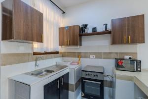 a small kitchen with a sink and a microwave at Wendy's Da-Azizi Homes Diani in Diani Beach