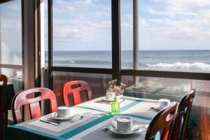 a table with chairs and a view of the ocean at Aparthotel Barracuda in Ponta Delgada