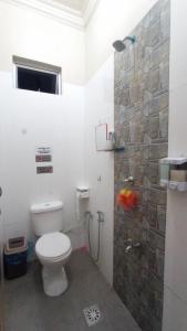 a bathroom with a toilet and a stone wall at Desa Besut Inn in Kampung Kuala Besut +10 photos