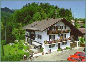 Großes weißes Haus mit Balkon auf einem Hügel in der Unterkunft Gästehaus Margarete in Bad Wiessee