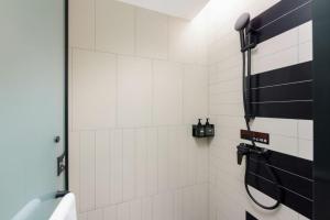 a bathroom with a shower with a black and white tile wall at Ibis Dalian Development Zone Wanda Plaza in Jinzhou