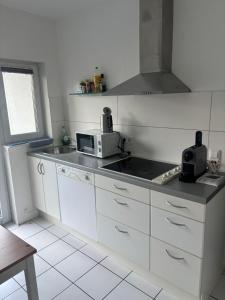 eine Küche mit weißen Schränken und einer Mikrowelle in der Unterkunft Business HO 03 in Neckarsulm