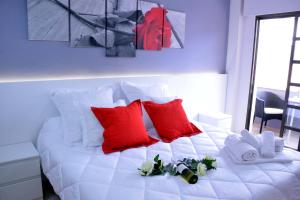 Una cama blanca con almohadas rojas y flores. en Hostal El Júcar, en Alcalá del Júcar