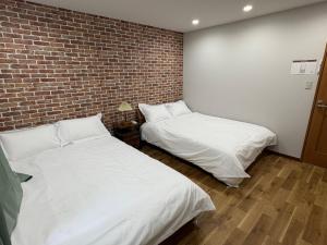 two beds in a room with a brick wall at 一休居 in Osaka