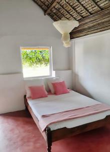 a bed with pink pillows in a room with a window at MBOTY Village in Vohemar