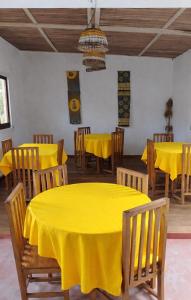 a dining room with yellow tables and wooden chairs at MBOTY Village in Vohemar +18 photos
