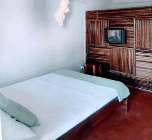 a bedroom with a bed and a tv on a wall at MBOTY Village in Vohemar