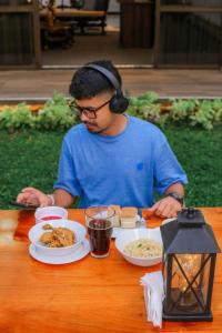 a man wearing headphones sitting at a table with food at BansriVilla Mount Lavinia in Mount Lavinia